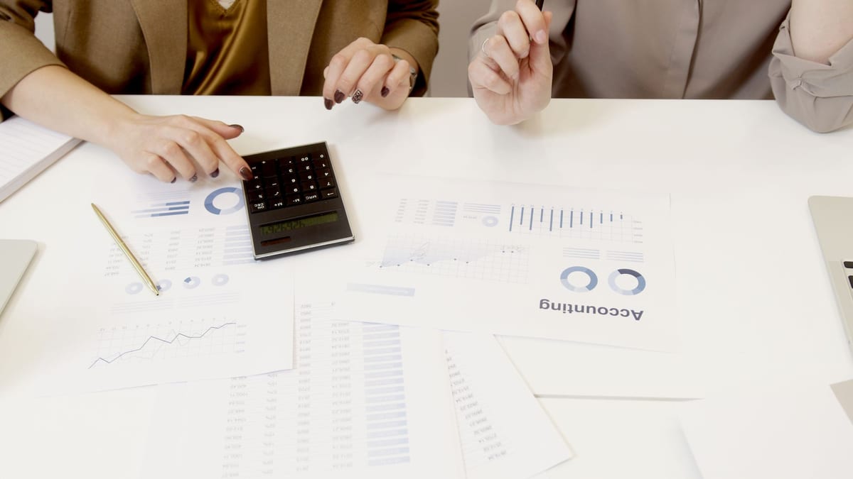 Accounting reports, charts and a calculator on a white table